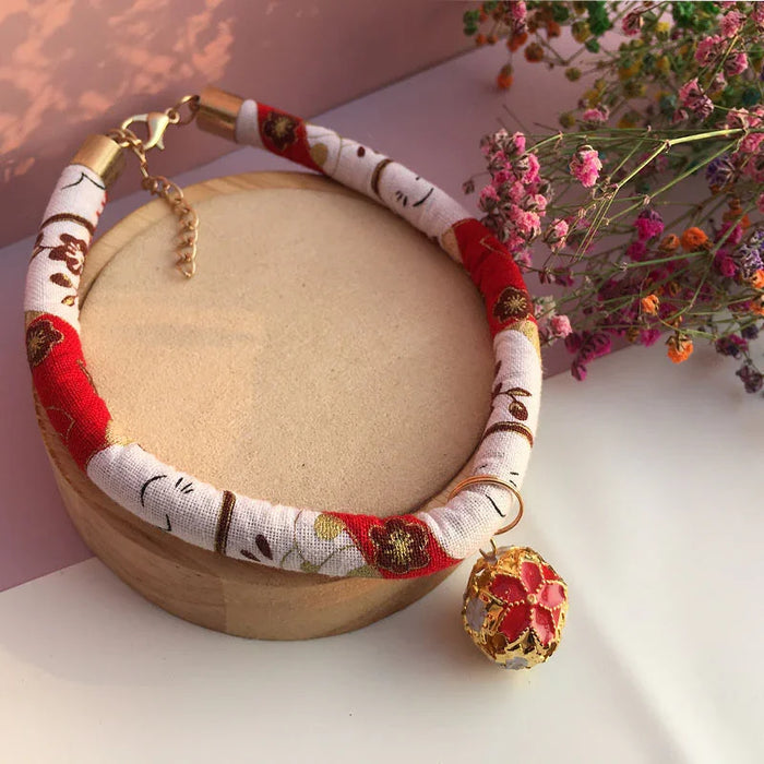 Floral pattern dog collar with gold bell charm, displayed on wooden stand with dried flowers