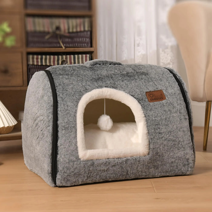 Gray plush pet bed with cozy white interior and hanging pom-pom toy, ideal for cats and small dogs.