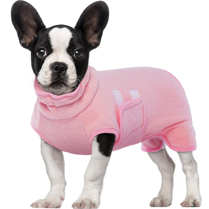 Small black and white French Bulldog wearing a cozy pink fleece dog sweater.