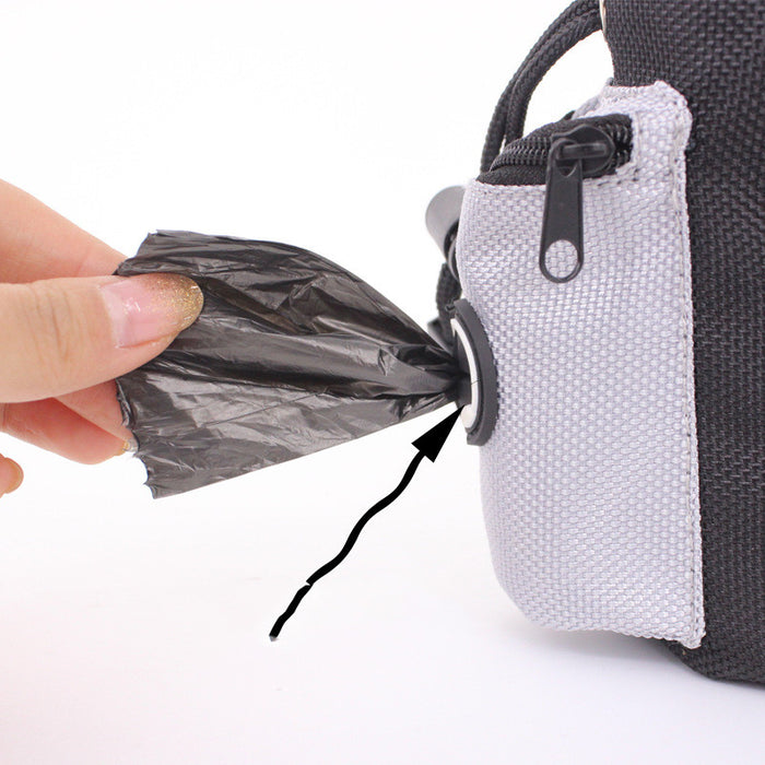 Hand pulling black poop bag from pet waste dispenser on gray and black carrier