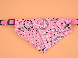 Pink bandana pet collar with white paisley patterns on a peach background.