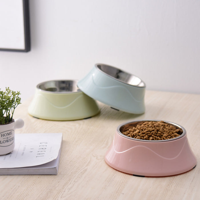 Pastel pet bowls with stainless steel inserts, one filled with dry kibble, on wooden table