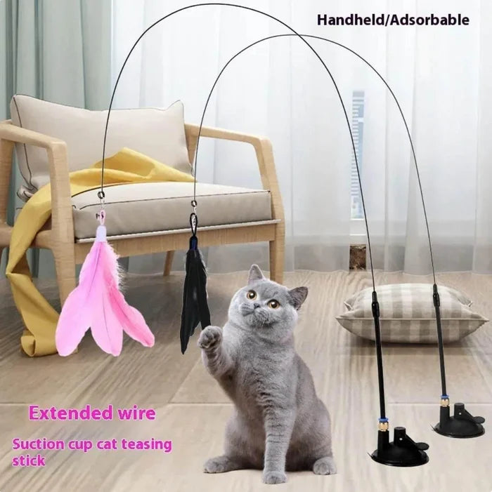 Gray cat playing with feather wand toy on suction cup stand, extended wire cat teaser stick