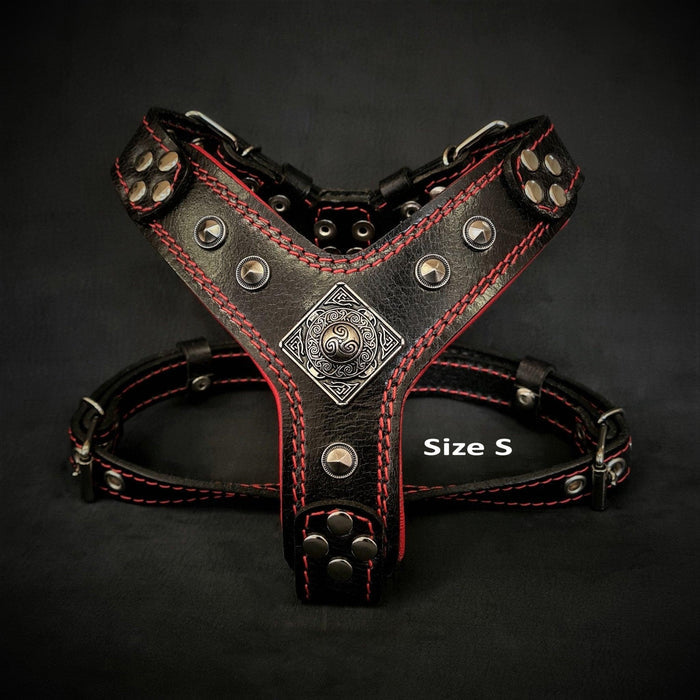 Black leather dog harness with red stitching, metal studs, and decorative emblem, Size S