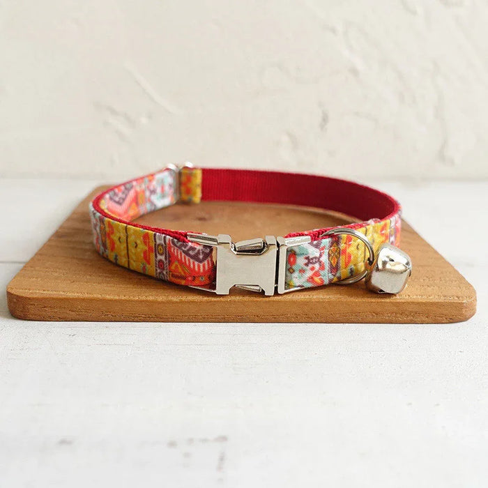 Colorful patterned cat collar with bell and metal buckle on wooden board