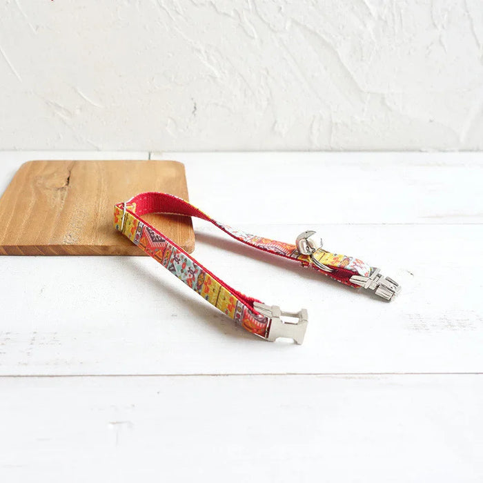 Colorful patterned cat collar with bell and breakaway buckle on wooden board